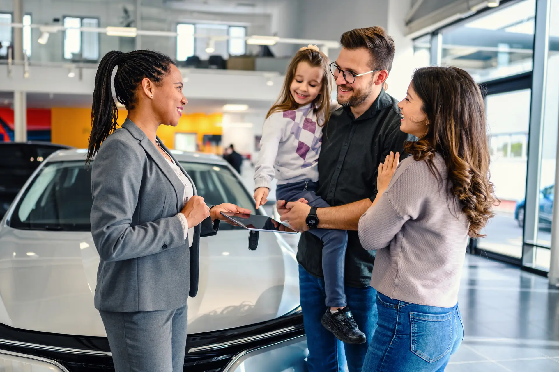 Saleswoman at car dealership center helping family to choose new family vehicle